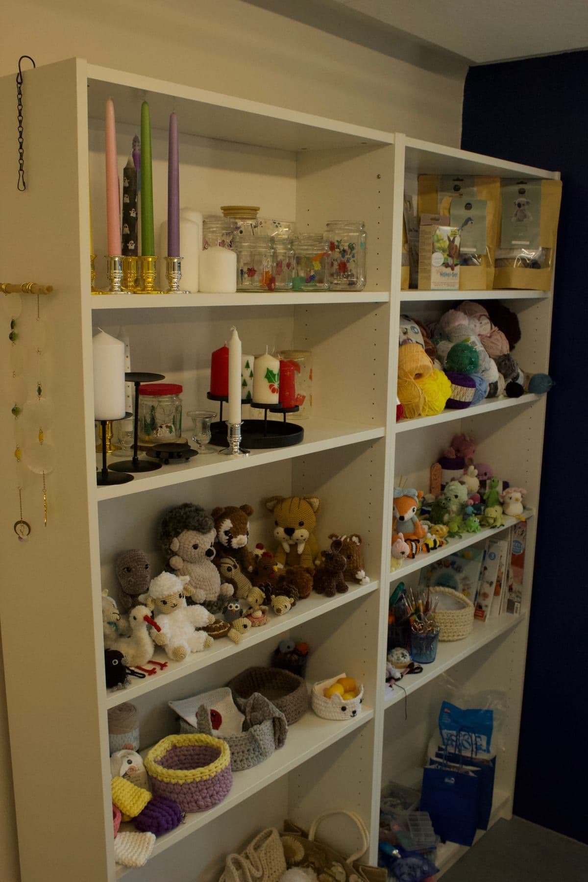 Shelves of crocheted animals, candles, and jars in the studio.