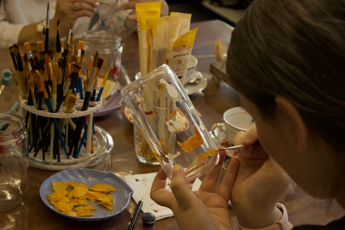 A participant painting a design onto a glass with a fine brush.