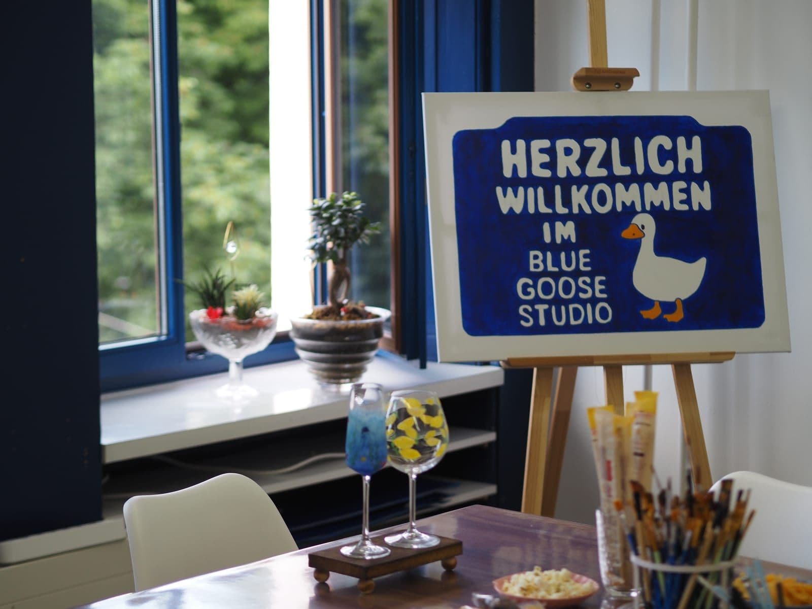 The blue Blue Goose Studio welcome sign on a sunlit windowsill.